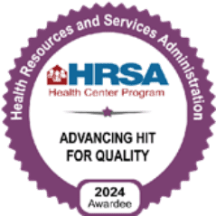A purple and white badge reads Health Resources and Services Administration, HRSA Health Center Program, Advancing HIT for Quality, 2024 Awardee—recognizing Grand Junction Health Care’s commitment to affordable health care.