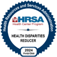 A blue and white badge reads: Health Resources and Services Administration HRSA Health Center Program. Grand Junction Health Care—Health Disparities Reducer. 2024 Awardee for Affordable Health Care.