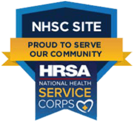 A badge with text: NHSC Site, Proud to Serve Our Community, HRSA National Health Service Corps, and a heart with a cross inside at the bottom, representing Montrose Health Care’s commitment to quality healthcare.